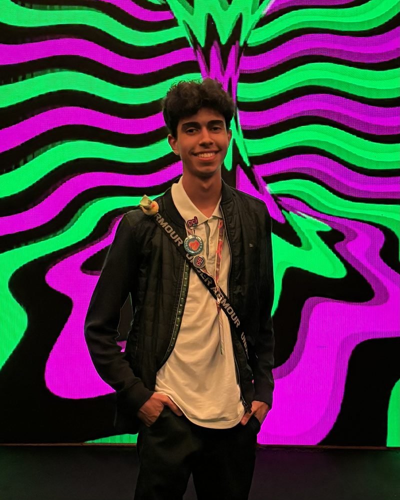 Vítor Pudim em frente ao telão verde e roxo do GO!RN 2026